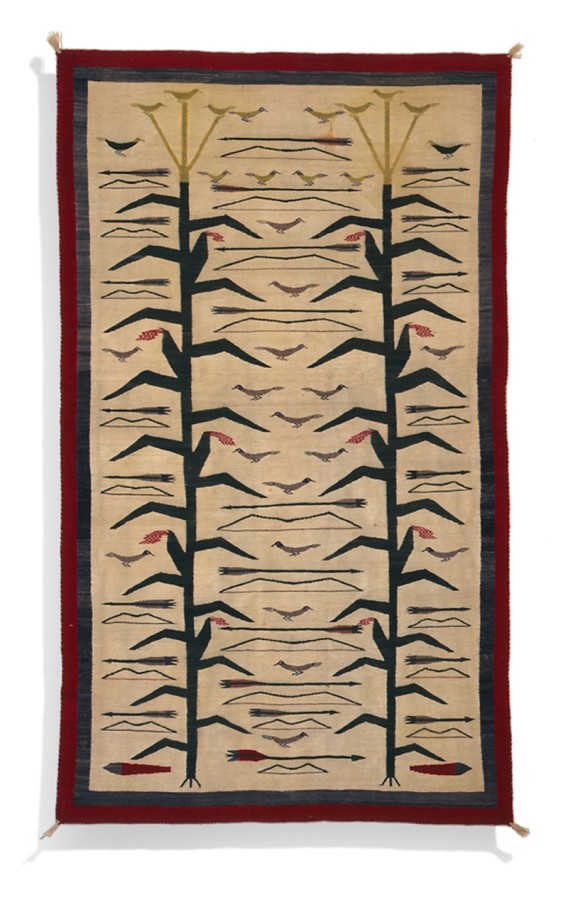 This Navajo rug is a weft tapestry woven of handspun wool. It depicts two stalks of corn with birds flying around the tops.