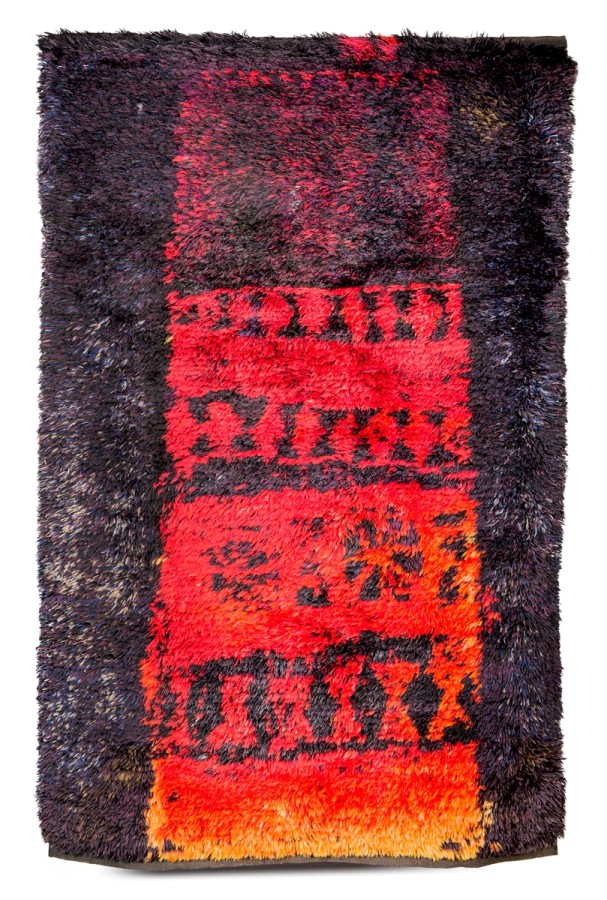 This is a thickly piled rug that consists of red, yellow and orange geometric designs down the center. The outer left and right sides are indigo.