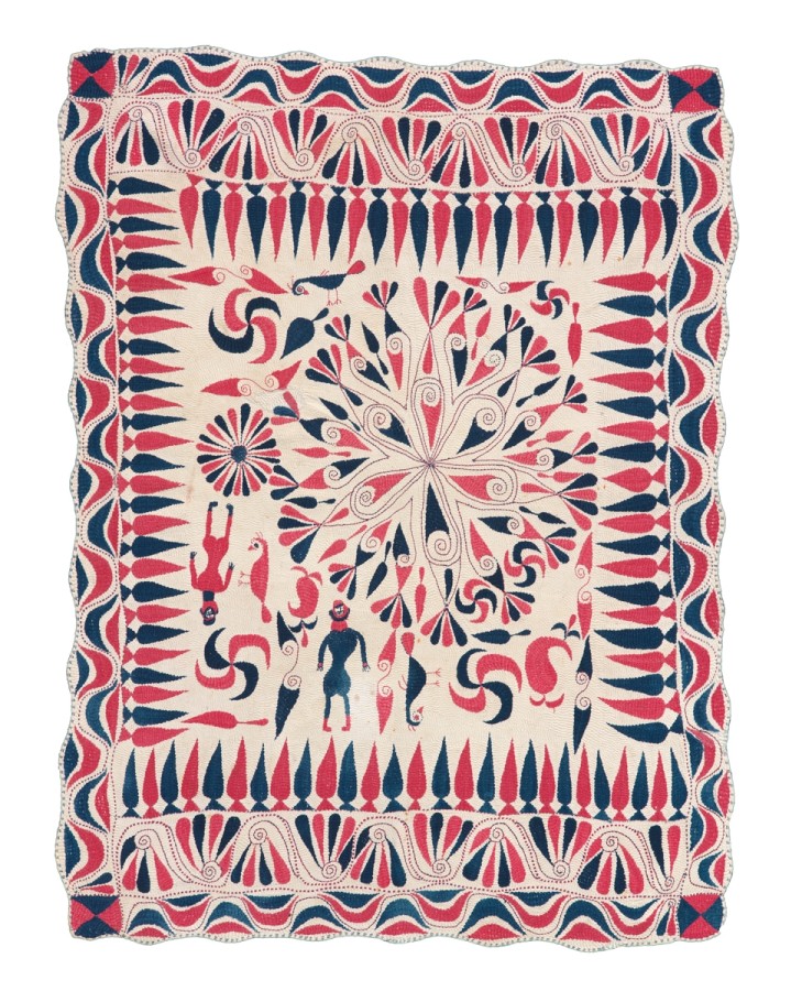 Embroidered in red and blue thread and quilted overall with an off-center medallion. The outer borders feature scrolling designs and stylized cypress trees. The inner area contains geometric motifs, human and animal figures, as well as swastikas.