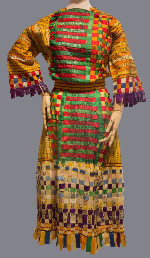 This dress is made of silk cigar bands and tobacco pouch labels. A package of ten or twenty cigars was held together by a colorful silk band advertising the tobacco brand. The bands and pouches vary in color, and most are yellow, purple, red, green, pink or blue.