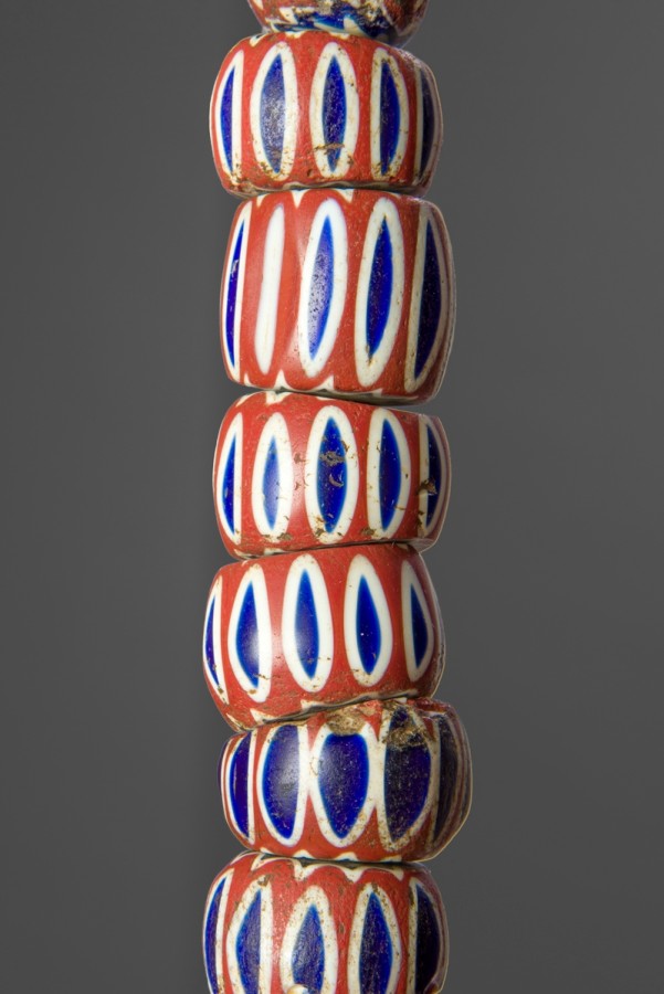 This bead strand is made of  varying size, shape, color and form. These beads have a terracotta colored base with blue ovals outlined with white encircling the bead.